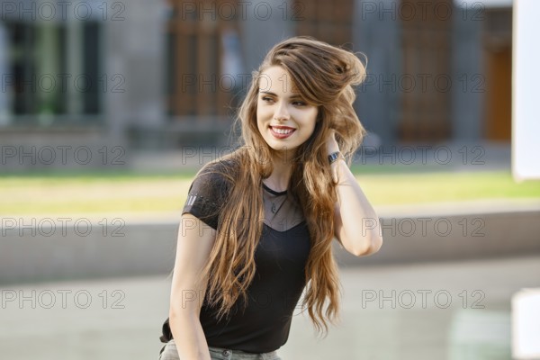 Positive and happy young woman with long curly hair outdoor