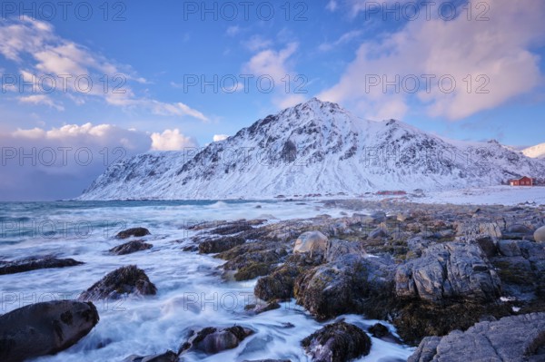 Beach of Norwegian sea on rocky coast in fjord on sunset in winter. Vareid beach, Lofoten islands, Norway, Europe
