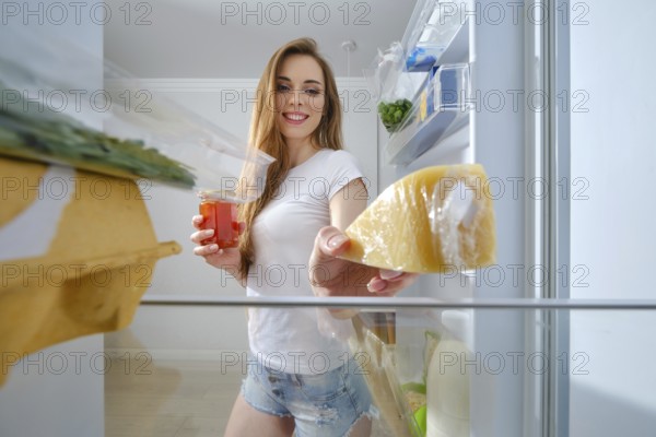 Young attractive woman is going to cook a healthy and good meal, she gets fresh food from the refrigerator. Healthy food concept