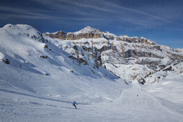 View of a ski resort piste with people skiing in Dolomites in Italy. Ski area Arabba. Arabba, Italy, Europe