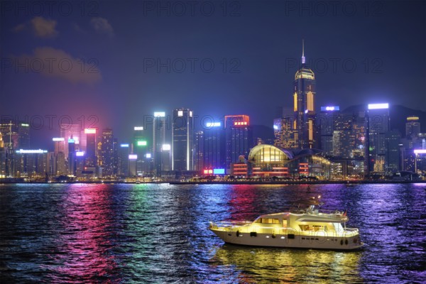 Hong Kong skyline cityscape downtown skyscrapers over Victoria Harbour in the evening illuminated with tourist boat ferries, Hong Kong, China, Asia