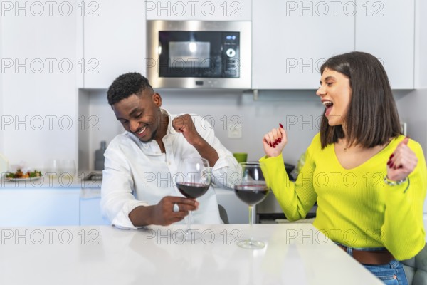 Multiethnic couple shares a joyful moment cooking burgers and drinking wine in a modern kitchen, highlighting togetherness and culinary delight