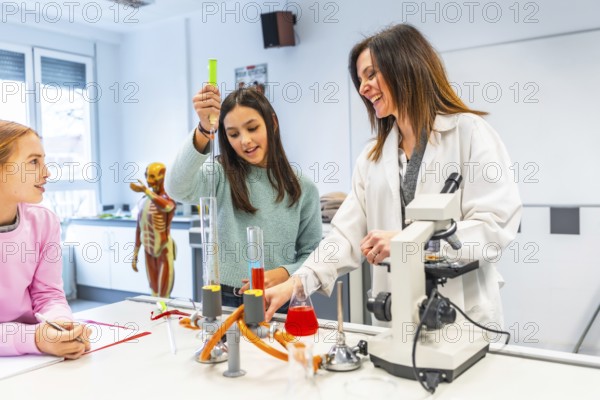 High school students learning chemistry with their teacher, using test tubes, flasks and microscope during a scientific experiment in the school laboratory