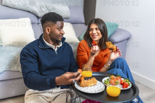 Couple sharing a cozy breakfast at home, enjoying fresh fruit, pastries, and juice, creating a warm and inviting atmosphere