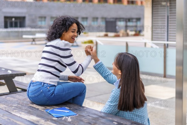 Students female multi-ethnic friends sitting in the campus of the university together talking and holding hands
