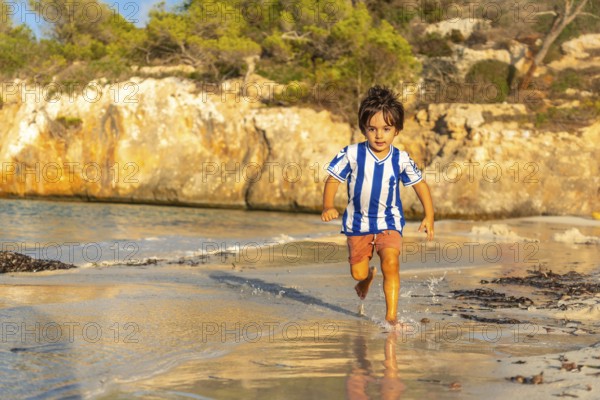 Carefree child enjoying summer holidays, running along the shore of s'amarador beach in mallorca, mediterranean sea