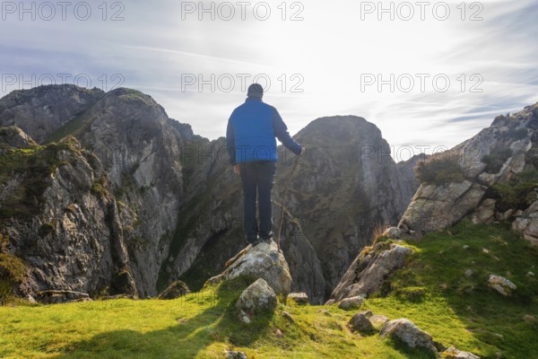 Hiker standing on a rock enjoying the breathtaking landscape of mount penas de aya in oiartzun, a stunning natural park in gipuzkoa, basque country