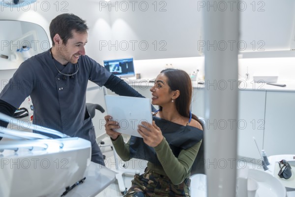 Dentist discussing teeth scan results with a smiling patient, showcasing modern dental technology and patient care in a bright, well equipped clinic