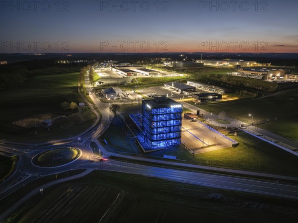 Illuminated modern building in an industrial area at night with a view of illuminated streets, Nagold, Black Forest, Germany, Europe