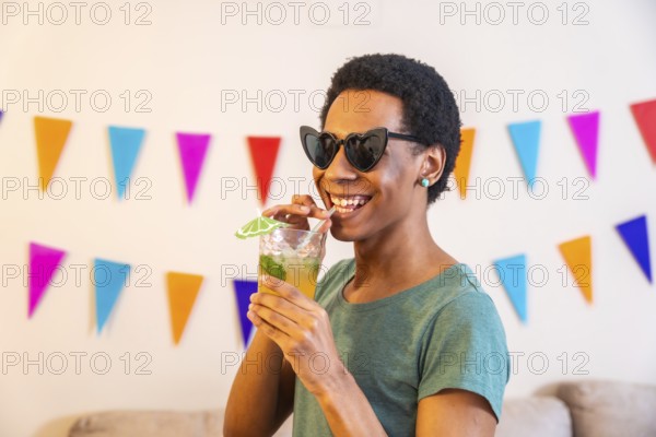 Latin cool man sucking a straw drinking cocktail partying at home