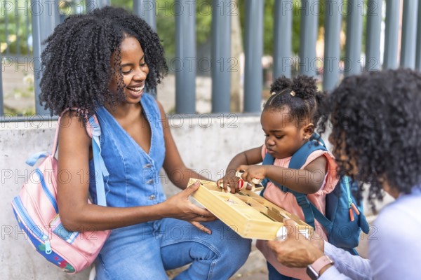 Three generation female african family playing outside school building