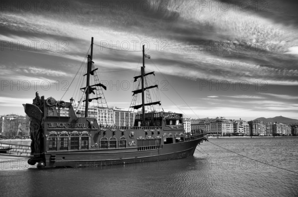 Tourist boat, excursion boat Black Pearl anchored, old harbour, view of waterfront, skyline of Thessaloniki, black and white, Thessaloniki, Macedonia, Greece, Europe
