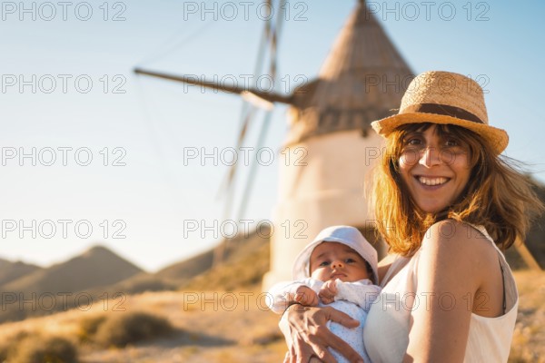 Mother with a baby in arms visiting traditional windmills in Cabo de Gata, Spain, Europe