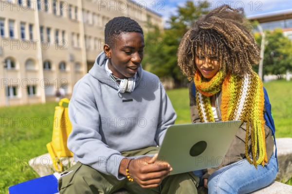 Two male and female multiraical students sitting with laptop on a bench at campus
