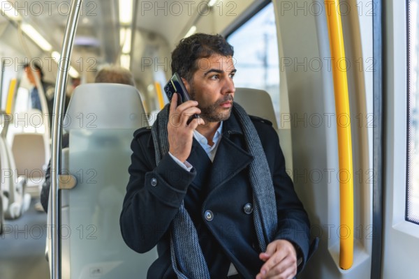 Handsome serious caucasian businessman looking through the window while talking to the mobile sitting on the metro