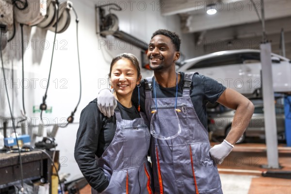 Two cheerful mechanics are posing together in a professional auto repair shop, showcasing teamwork and expertise in the automotive industry