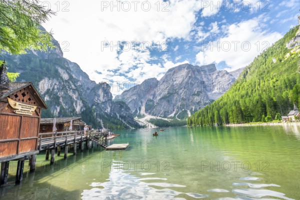 Tourists kayaking on the serene emerald waters of lake braies, surrounded by the breathtaking dolomites on a summer day