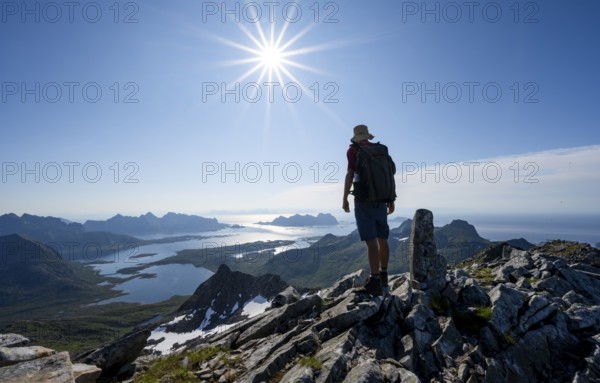View of mountains and fjord landscape, mountaineer at the summit of Rundfjellet, Sun Star, Austenesfjord fjord, Svolvaer, Nordland, Norway, Europe