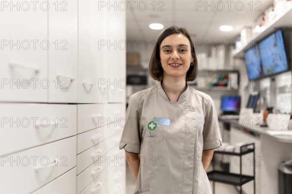 Young and proud female pharmacist standing with arms in the back in the storage room in a modern shop