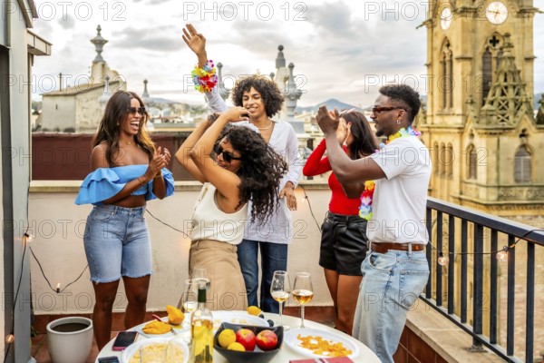 Excited multi-ethnic friends dancing during rooftop evening party in the city