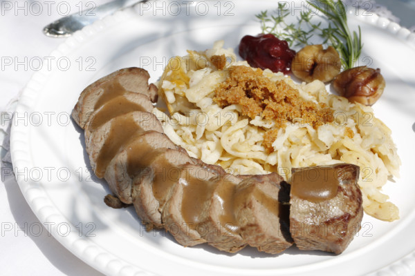 Swabian cuisine, roast venison with spaetzle, chestnuts and breadcrumbs, breadcrumbs, saddle of venison arranged on a plate, gravy, game dish, meat, main course, gravy, cutlery, knife, fork, grandmother's kitchen, regional, home cooking, typical Swabian, traditional cuisine, food photography, studio, Germany, Europe