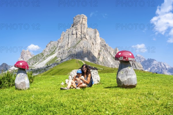 Mother and child are resting near wooden mushrooms at giau pass, a high mountain pass in the dolomites, italy