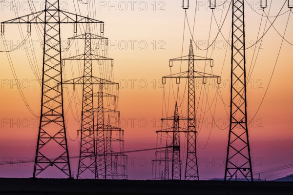 High-voltage pylons, overhead power lines at sunset. Schwieberdingen, Baden-Württemberg, Germany, Europe