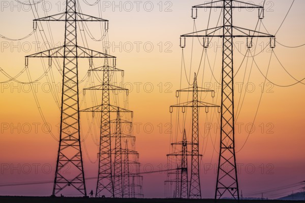 High-voltage pylons, overhead power lines at sunset. Schwieberdingen, Baden-Württemberg, Germany, Europe