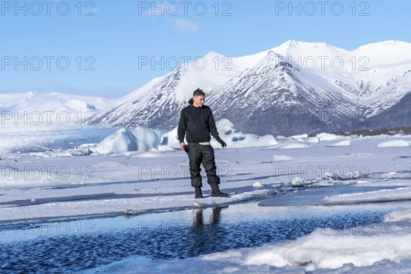 An adventurous young man walking on the frozen Jokulsarlon lake in winter in Iceland