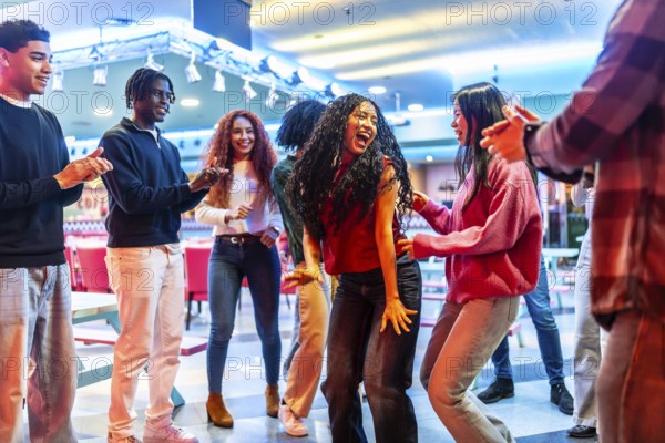 Cheerful multi ethnic friends dancing joyfully and enjoying their time together at the lively bowling alley, creating unforgettable memories