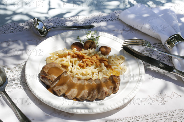 Swabian cuisine, roast venison with spaetzle, chestnuts and breadcrumbs, breadcrumbs, saddle of venison arranged on a plate, gravy, game dish, meat, main course, gravy, cutlery, knife, fork, grandmother's kitchen, regional, home cooking, typical Swabian, traditional cuisine, festive tablecloth, food photography, studio, Germany, Europe