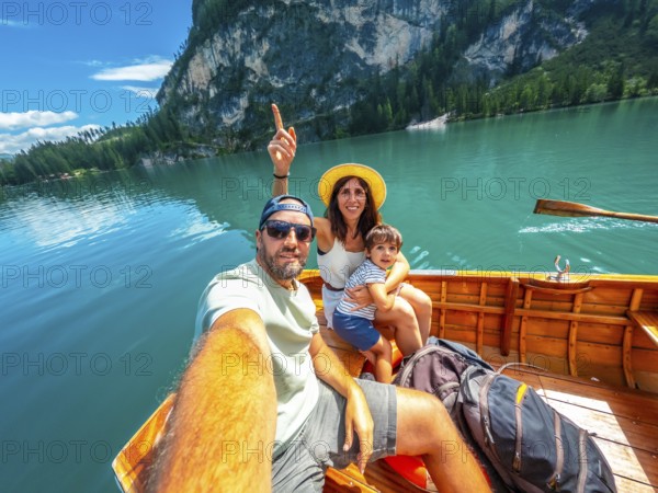 Family taking a selfie while enjoying a boat trip on the beautiful lake braies, surrounded by the stunning dolomites mountains in italy
