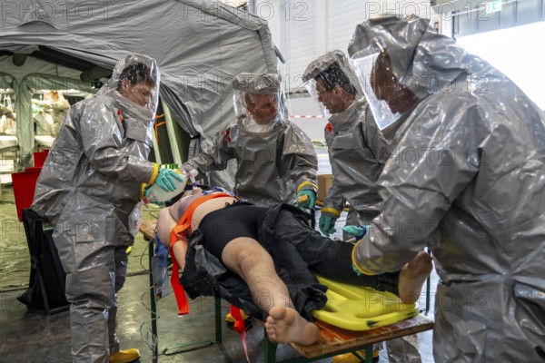 Decontamination of injured persons after an assumed accident involving hazardous substances, fire brigade and aid organisations practise setting up and operating a decontamination station, injured persons are sighted and then washed in a special shower tent to remove possible hazardous substances and chemicals in order to avoid further injuries, the emergency services wear special, ventilated protective suits, large-scale exercise by the Essen fire brigade