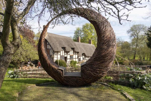 Anne Hathaway's Cottage framed by a round wicker seat, Shottery, Stratford-upon-Avon, Warwickshire, England, United Kingdom, Europe