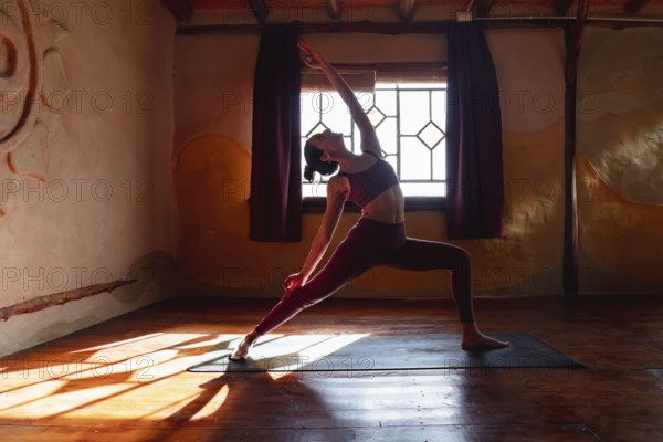 Young slim woman doing yoga on a mat, warrior pose. Posture of strength and balance. Concept of healthy living