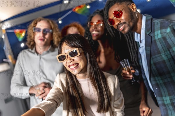 Chinese woman with elegant clothes and sunglasses taking selfie while enjoying night party with multi-ethnic friends