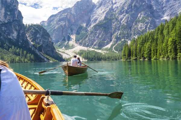 Tourists enjoying a boat trip on the stunning lake braies, surrounded by the breathtaking scenery of the dolomites in summer