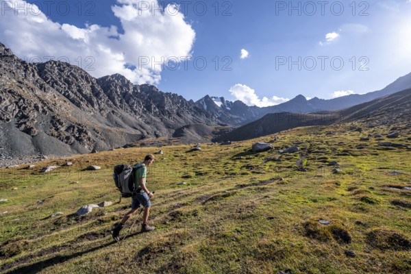 Mountaineers on a hiking trail, green high valley in atmospheric light, Keldike Valley on the way to the Ala Kul Pass, Tien Shan Mountains, Kyrgyzstan, Asia