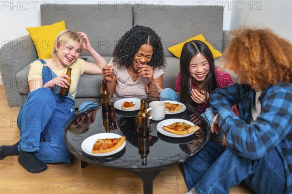 Four female friends sharing a meal of pizza and beer, laughing and having fun together in their living room