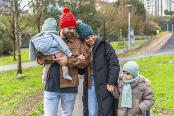 Smiling parents walking with their children in a park on a chilly winter day, enjoying moments of joy and togetherness amidst nature