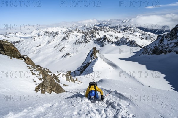 Mountaineer with ice axe and crampons, ascent through steep snowfield to Piz Kesch or Piz d'Es-cha in winter, view of mountain panorama with Vadret da Porchabella glacier, Albula Alps, Rhaetian Alps, Grisons, Eastern Switzerland, Switzerland, Europe