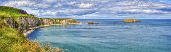 Long coastline with steep cliffs and calm blue sea under cloudy skies, County Antrim Coast
