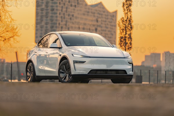 White electric car in urban environment with modern architecture and sunset, Tesla New Model Y, Germany, Europe