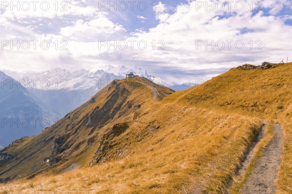 A narrow path leads over an autumnal mountain ridge under a cloudy sky, Planplatten, Switzerland, Europe