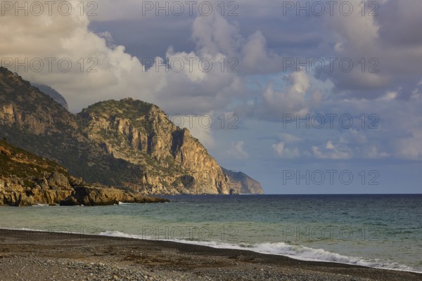 Rocky cliffs on the coast with foamy waves and a dramatic cloudy sky in the distance, south coast, Lefka Ori, White Mountains, mountain massif, west, Crete, Greece, Europe