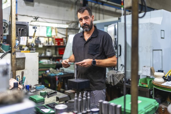 Male caucasian operator performing quality control on metal pieces in the factory using a micrometer