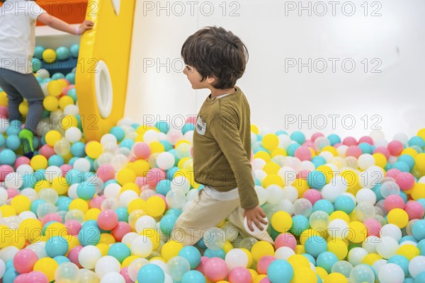 Young boy joyfully playing in a vibrant ball pit, surrounded by a colorful playground that sparks imagination and happiness