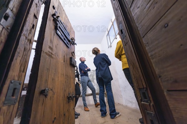 Several people standing in a room with large wooden doors and a historical appearance, Prison Museum, Der Lange, Calw, Black Forest, Germany, Europe