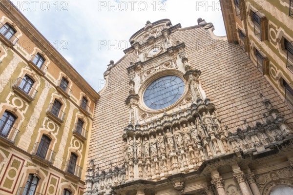 Low angle view of the montserrat monastery facade, featuring sculptures of biblical figures and a clock, located in catalonia, spain