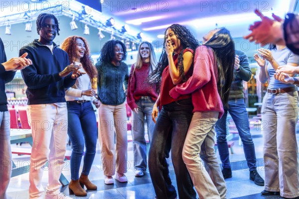Group of young multiethnic friends enjoying a weekend together dancing and having fun in a bowling alley